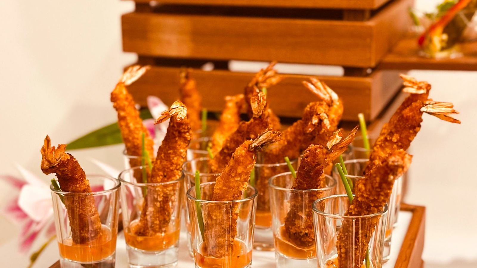 Crisp prawn shooters served in glasses on a wooden riser