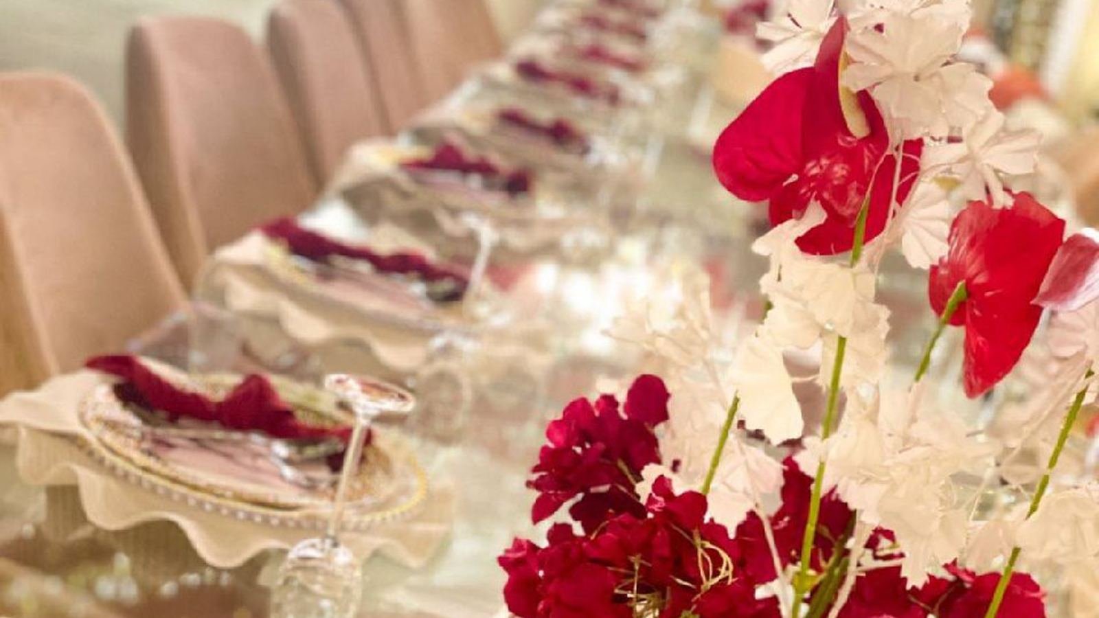 Long banquet table dressed with crystal and deep red bougainvillea for a Dana Prime event