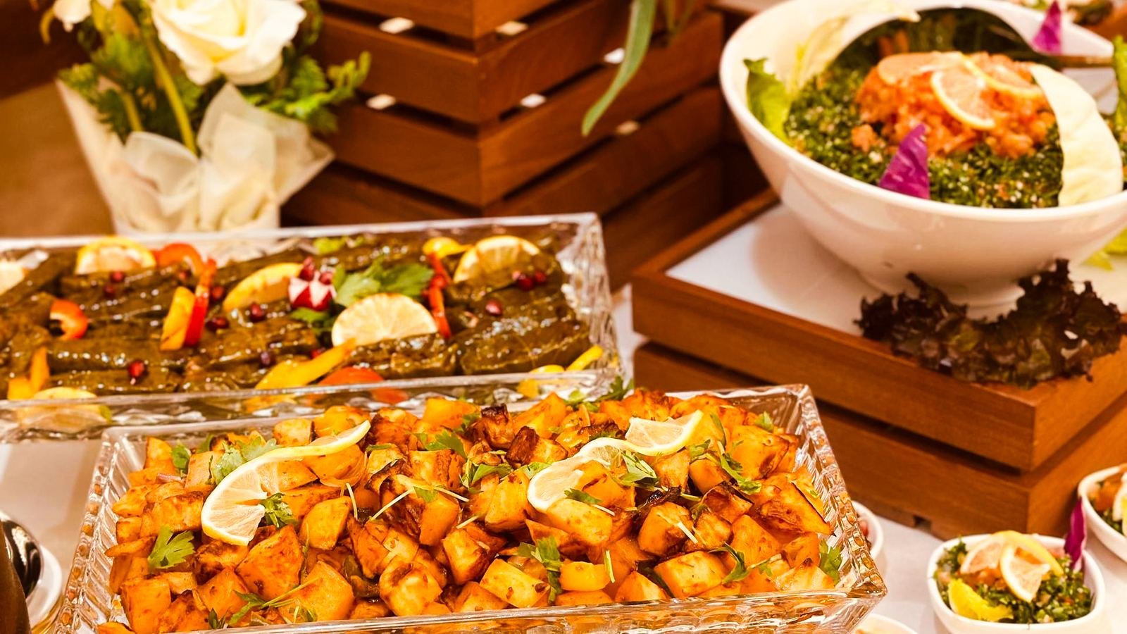 Mezze, vine leaves and spiced potatoes presented on wooden risers from the Dana Prime menu