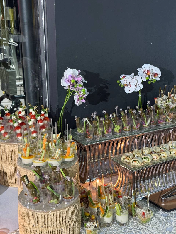 Tiered canape service with individual vegetable cups, wraps and orchid arrangements