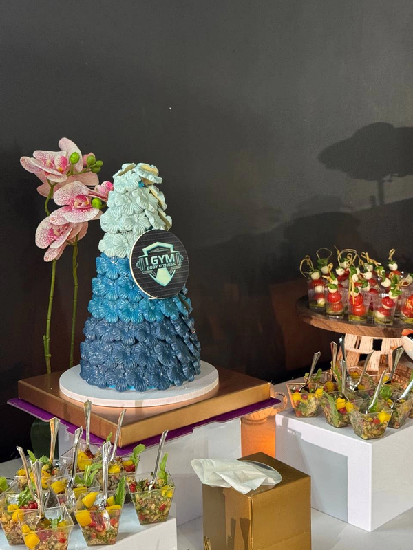 Blue and ivory celebration cake beside orchids and individual salad cups