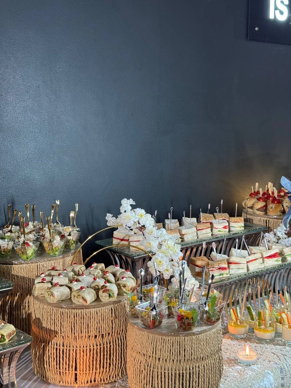 Full catering display of wraps, sandwiches, salad cups and floral arrangements