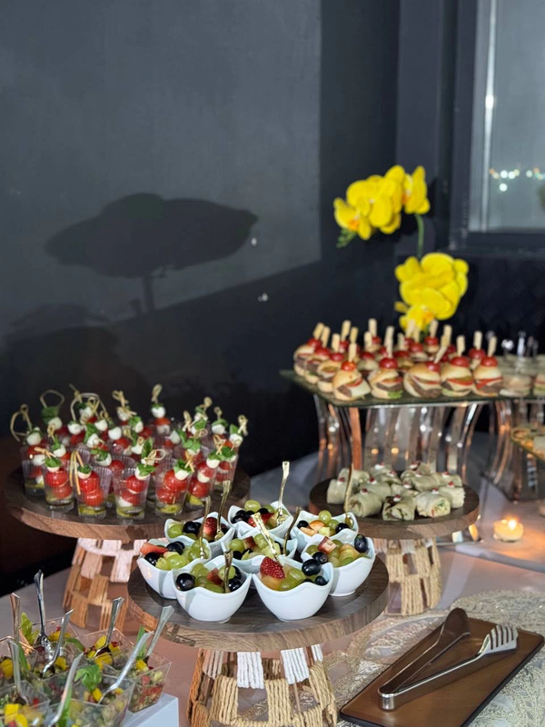 Fruit bowls, canape skewers, wraps and miniature burgers on a catering table