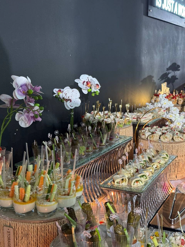 Orchid-lined buffet presentation with vegetable cups, wraps and salads