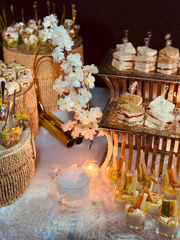 Sandwich and vegetable-cup presentation with white orchids and warm table lighting